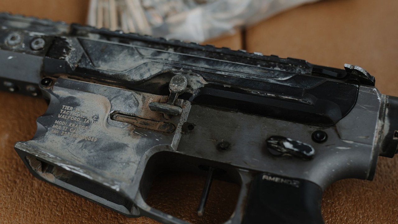 Carbon covered Tier 1 receiver beside a bag of spent brass after endurance testing