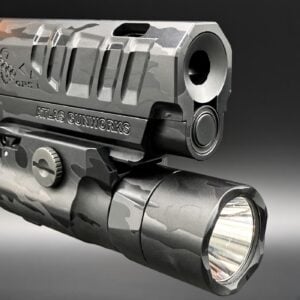 Close-up of a camouflaged handgun accessory rail with a mounted tactical light.