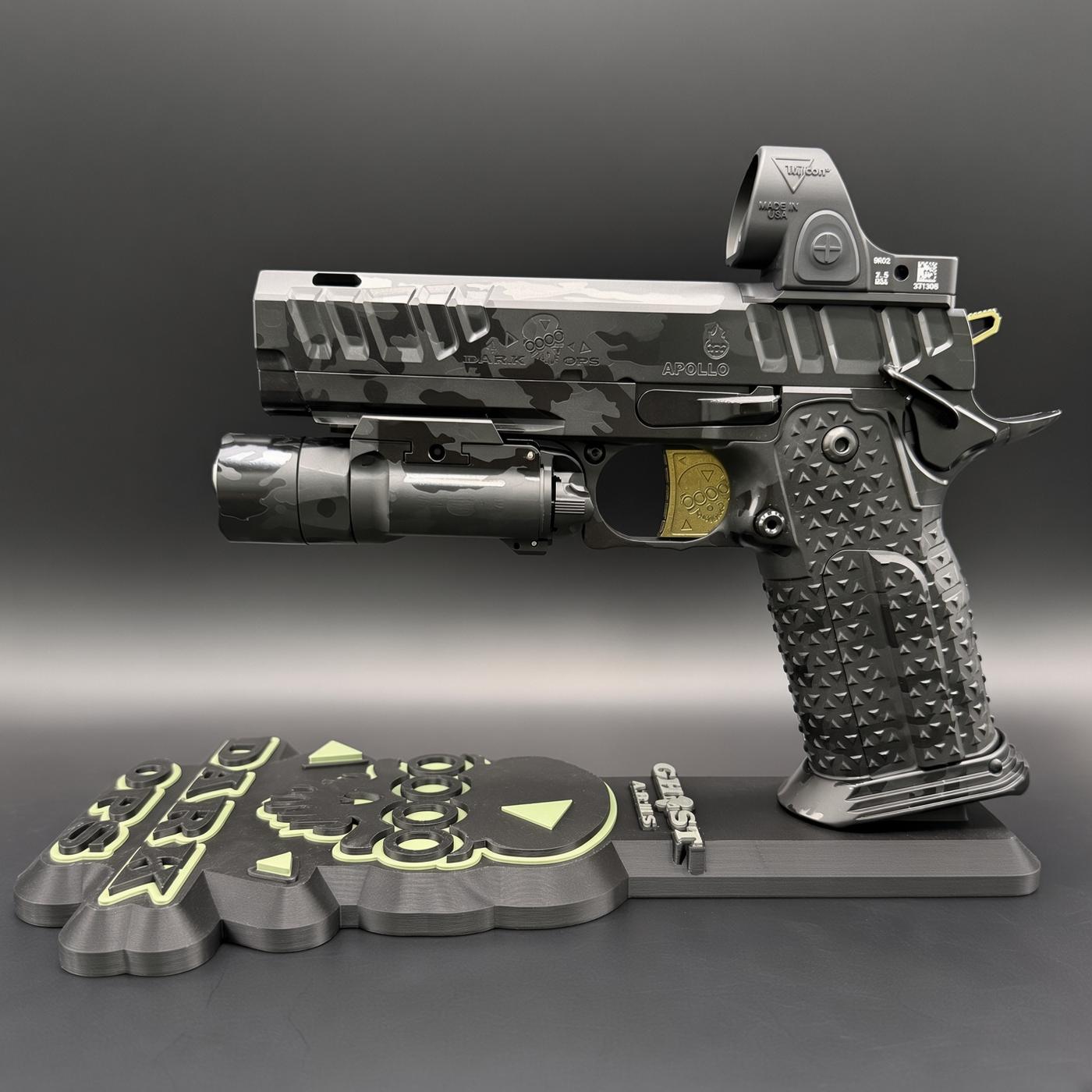 Detail shot of a camo-pattern pistol with a tactical grip and underside accessory, mounted on a decorative base with embossed yellow-green symbols.