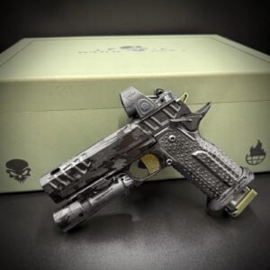 Camouflage-patterned tactical rifle with a red-dot sight, resting on a green storage case with a skull logo.