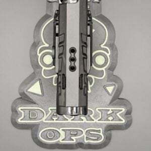 Close-up of a pistol slide mounted in a jig with a decorative 'DARK OPS' logo in the background.