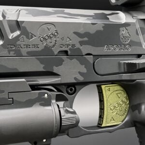 Close-up of a camouflaged firearm receiver with 'DARK OPS' and 'APOLLO' engravings and a gold magazine.