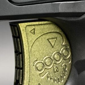 Close-up of a gold-toned combination dial on a dark metal lock, showing circular knobs and triangular direction markers.